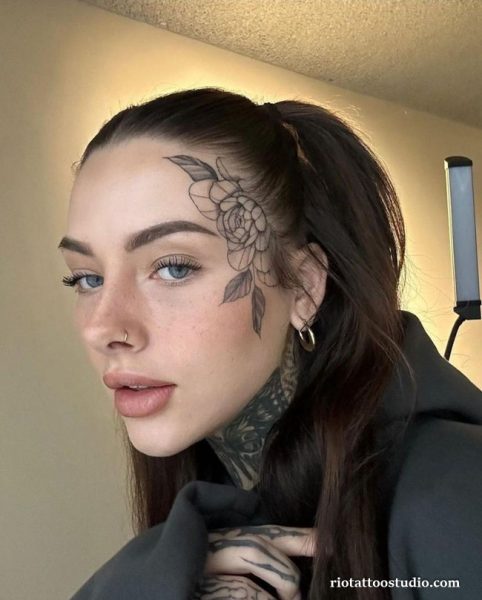 Rose face tattoo with leaves across forehead temple, feminine bold face tattoo