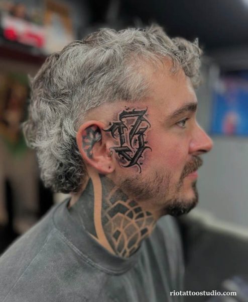 Tribal thorn wing face tattoo wrapping side face neck, edgy bold face tattoo