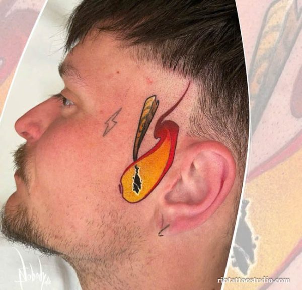 Color dagger flame lightning face tattoo on temple side, bold small face tattoo