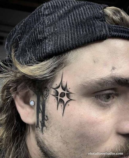 Starburst face tattoo with gothic frame vines on temple, artistic bold face tattoo