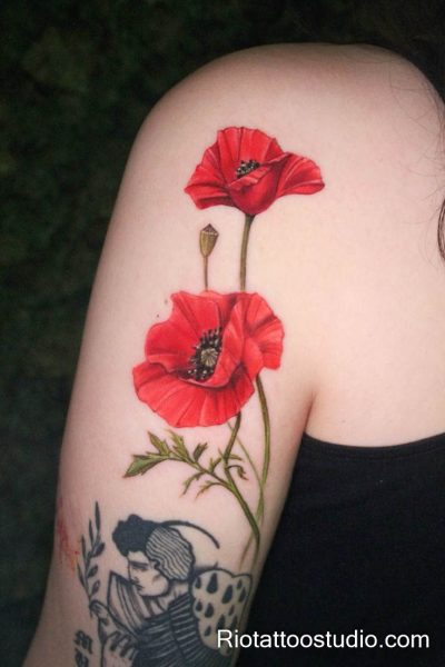 Realistic pink rose with watercolor splatter on forearm, feminine flower tattoo