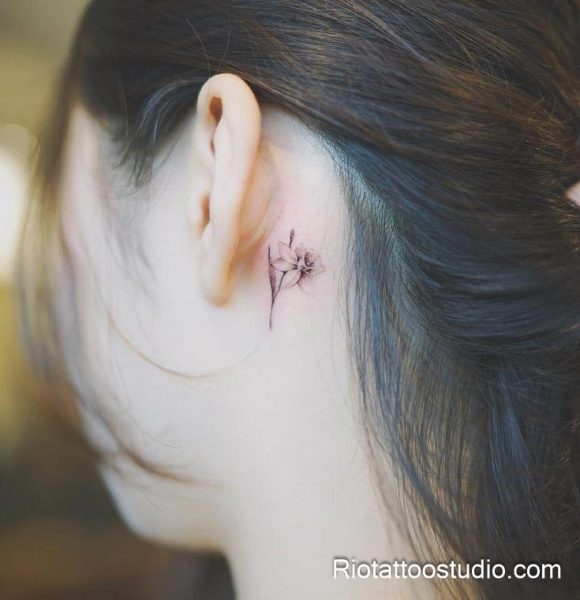 Tiny black outline flower tattoo behind the ear, minimalist feminine floral tattoo