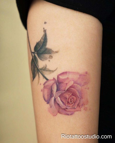 Pink watercolor rose with leaves on forearm, feminine flower tattoo design