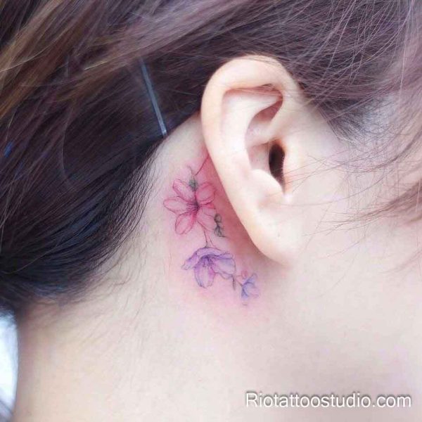 Delicate pink and purple watercolor flowers behind the ear, tiny feminine flower tattoo