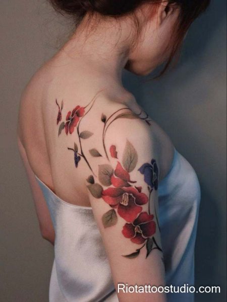 Realistic pink-red bougainvillea flowers on shoulder and upper back arm, feminine floral tattoo