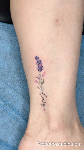 Blue lily-of-the-valley flowers with "parkji year" script on forearm, feminine tattoo