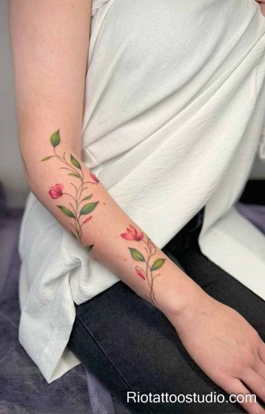 Red-purple blooming flowers with buds on forearm, feminine floral tattoo for women