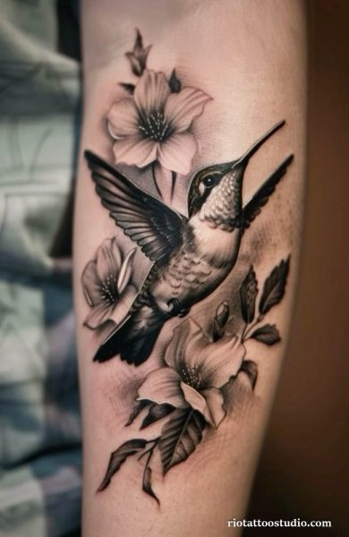 Black and grey hummingbird tattoo with orchids on chest, elegant floral hummingbird tattoo