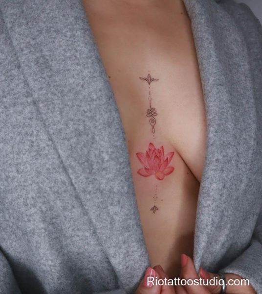 Small pink lotus flower tattoo with geometric dots on chest rib, minimalist lotus tattoo