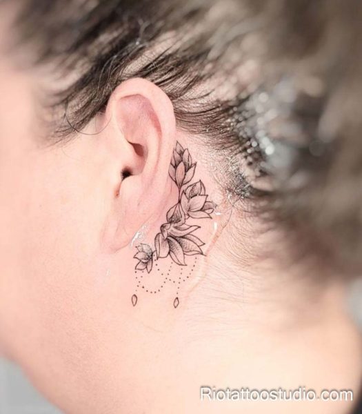 Tiny lotus flower with dotted chain behind the ear, feminine behind-the-ear tattoo