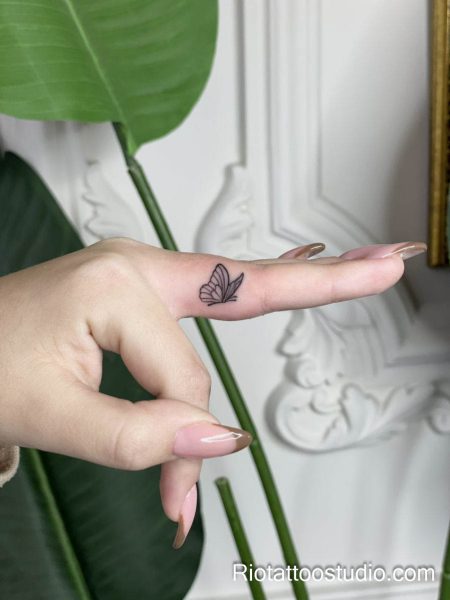 Micro finger black butterfly tattoo on finger, minimalist tiny tattoo