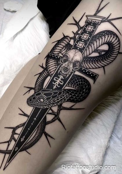Snake skull dagger tattoo with thorns on forearm, dark snake tattoo