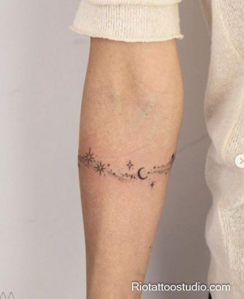 Minimal radiant starburst tattoo with scattered stars on arm, small star tattoo