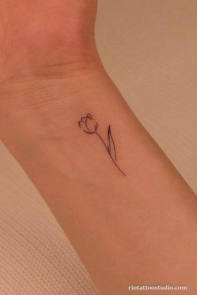 Minimal tulip flower wrist tattoo in black outline, delicate floral wrist tattoo