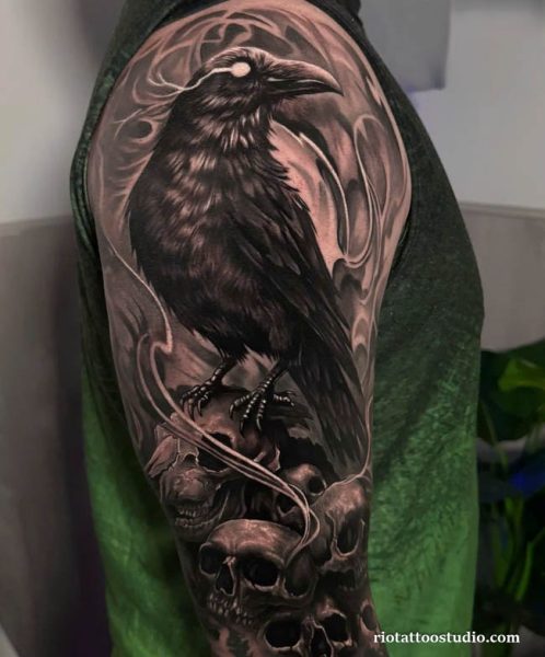 Large realistic crow tattoo with skulls on shoulder and arm, hyper realistic crow tattoo ideas