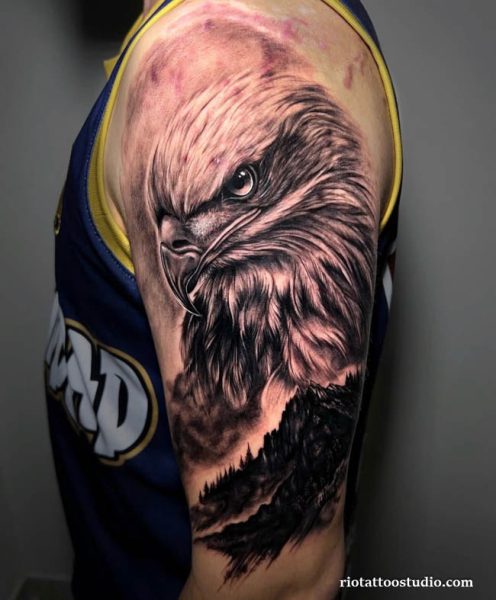 Ultra-realistic eagle head tattoo on upper arm capturing a sharp, commanding gaze.