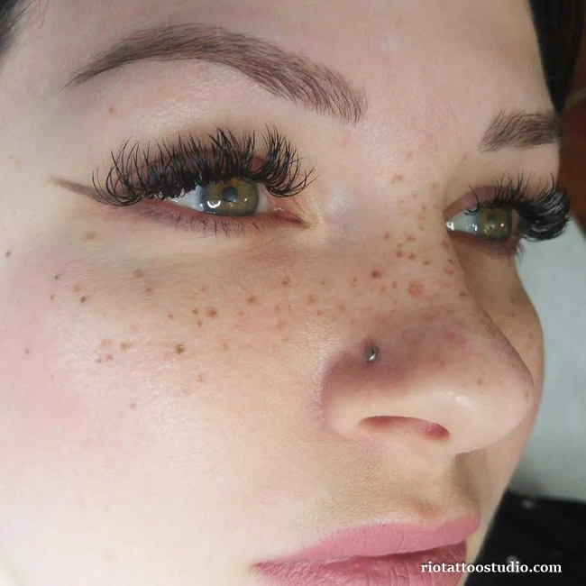 A delicate tattoo design of tiny wildflowers intertwined with freckles and tattoos, creating a whimsical and feminine look at Rio Tattoo Studio.