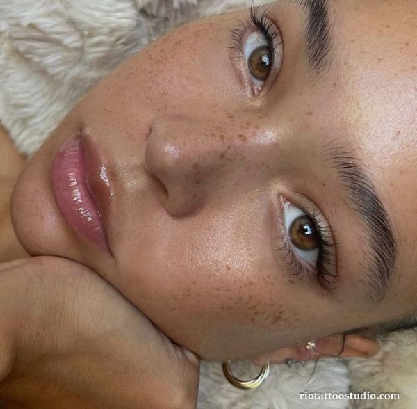 A sophisticated and elegant woman showcasing her freckles tattoo, embodying the modern definition of style and luxury.