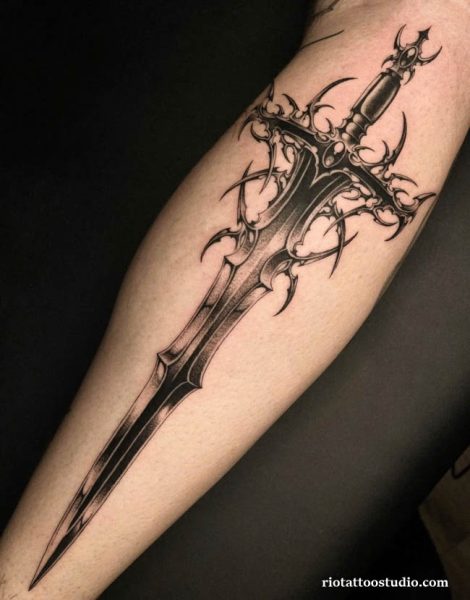 Ornate dark fantasy sword tattoo with thorns and intricate hilt on upper arm, gothic sword tattoo ideas