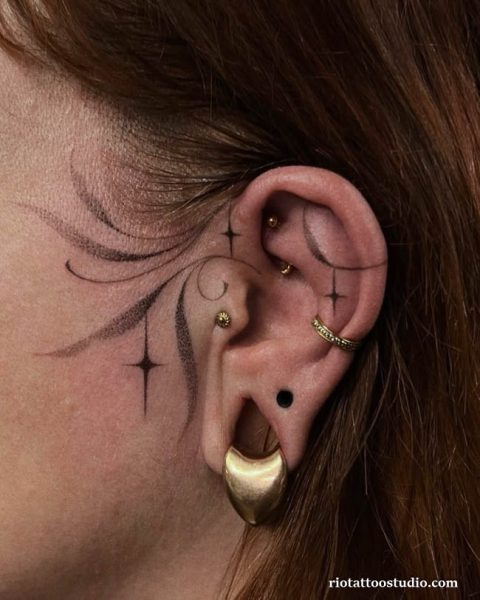 Star and swirl ear tattoos with multiple piercings on cartilage and lobe, minimalist ear tattoos ideas