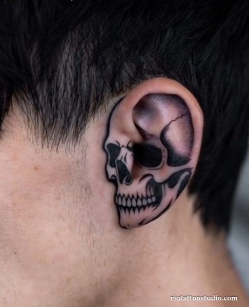 Realistic skull ear tattoos covering the entire ear with black and grey shading, bold ear tattoos ideas
