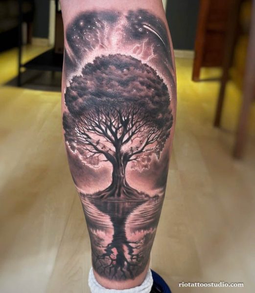 Realistic tree tattoo with reflection in water, starry night sky and lightning on calf, dramatic tree tattoo ideas