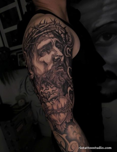 Realistic chicano tattoo of Jesus Christ with crown of thorns and sacred heart on shoulder and arm