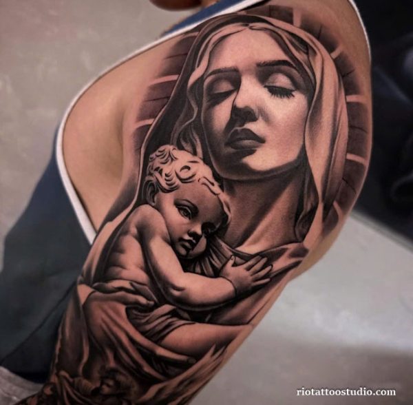 Realistic black and grey chicano tattoo of Virgin Mary holding baby Jesus on shoulder, religious chicano tattoo ideas