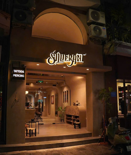 Night view of Silver Ant Tattoo studio entrance in Hanoi with illuminated sign and professional tattoo & piercing setup for coverups tattoo