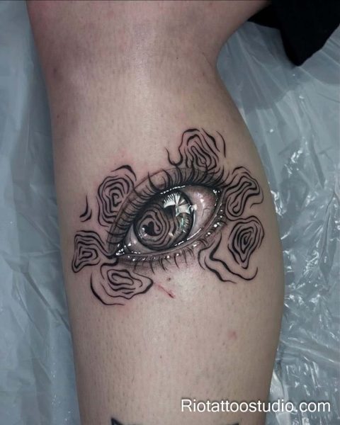 Realistic evil eye tattoo with swirling smoke and detailed iris on knee, evil eye tattoo ideas