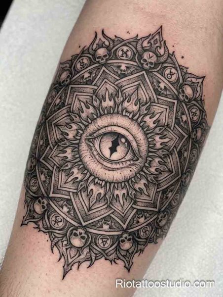 Large intricate mandala evil eye tattoo with skulls, flames and sacred geometry on arm, evil eye tattoo ideas