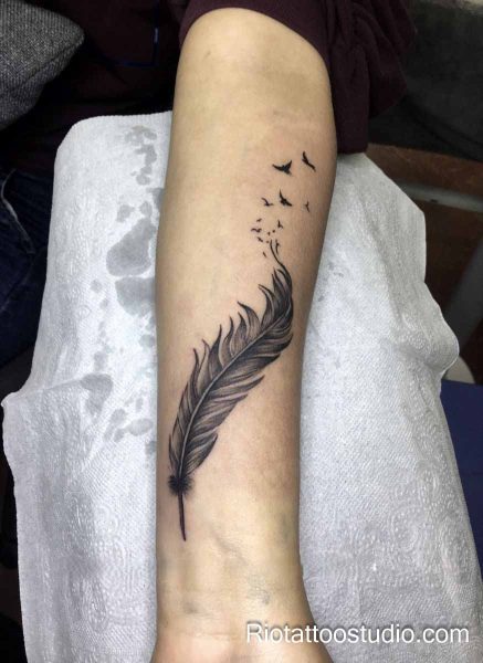 Black and gray feather tattoo with flock of birds flying upward on arm, realistic feather tattoo ideas
