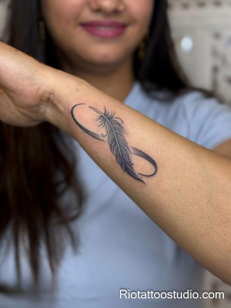 Minimalist infinity feather tattoo in black on inner forearm, simple feather tattoo ideas