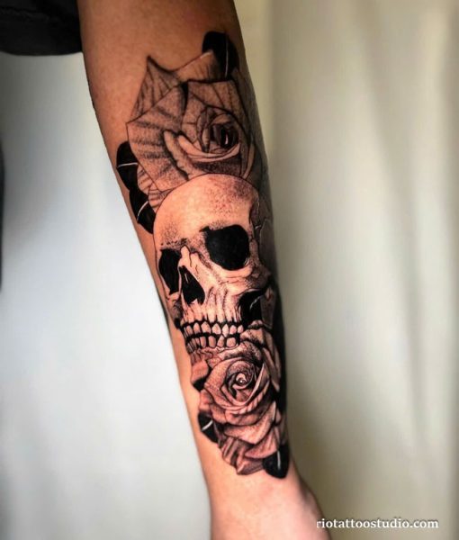 Realistic skull and rose half sleeve tattoo in black and grey on forearm