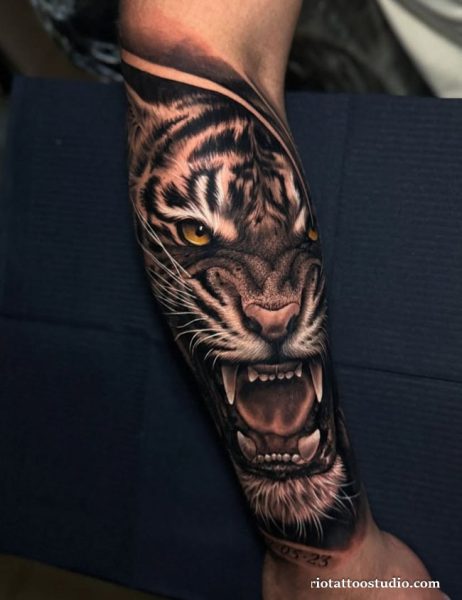 Realistic tiger half sleeve tattoo with fierce roaring tiger and yellow eyes on forearm
