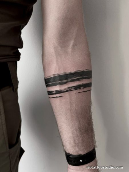 Minimalist abstract brush stroke half sleeve tattoo with bold black lines on forearm