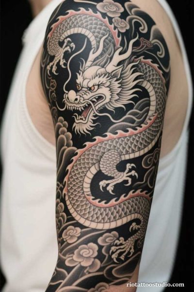 Black and grey Japanese dragon tattoo sleeve with white dragon, clouds and cherry blossoms on arm, japanese dragon tattoo ideas