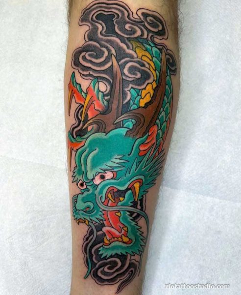 Vibrant green Japanese dragon head tattoo with colorful clouds and horns on the leg, japanese dragon tattoo ideas