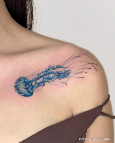 Watercolor blue jellyfish tattoo with flowing tentacles on shoulder and collarbone, jellyfish tattoo ideas