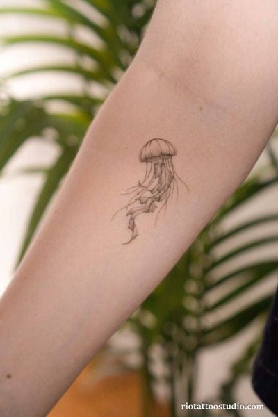 Delicate fine line jellyfish tattoo with detailed bell and flowing tentacles on upper arm, jellyfish tattoo ideas