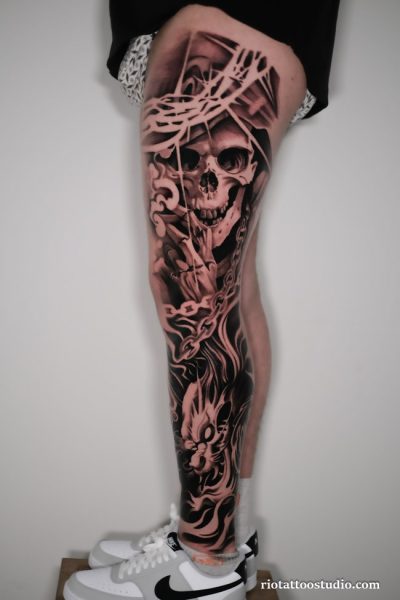 Hyper-realistic skull leg sleeve tattoo with chains, broken glass and flames on thigh and leg, dark leg sleeve tattoo ideas