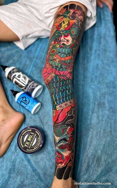 Japanese samurai leg sleeve tattoo with warrior helmet and demon face in full color, colorful leg sleeve tattoo ideas