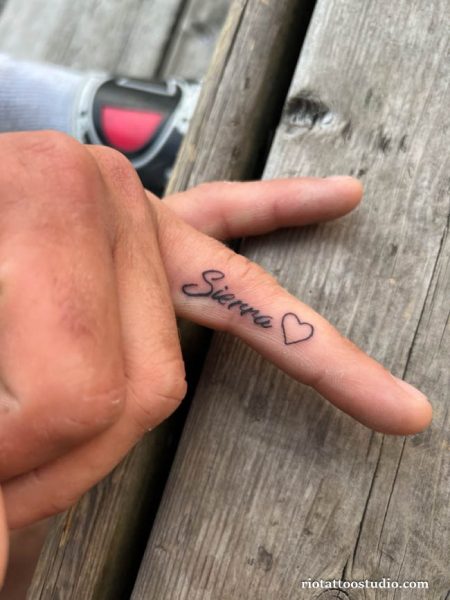 Tiny finger name tattoo "Sierra" in cursive script with small heart, name tattoo ideas
