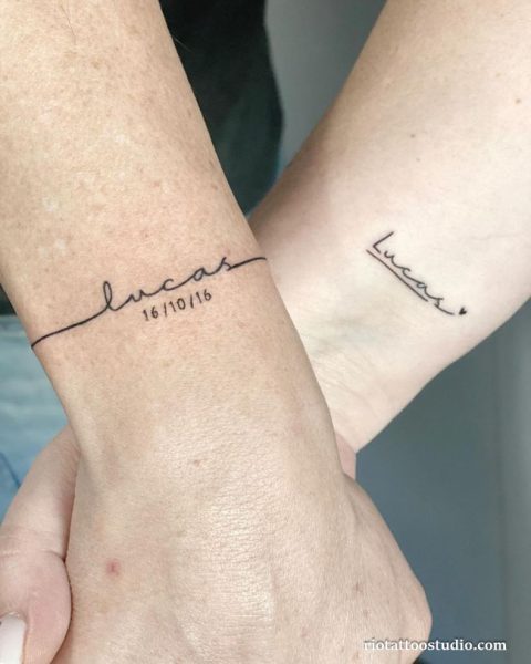 Matching couple name tattoos "Lucas" in script with date and arrow on wrists, name tattoo ideas