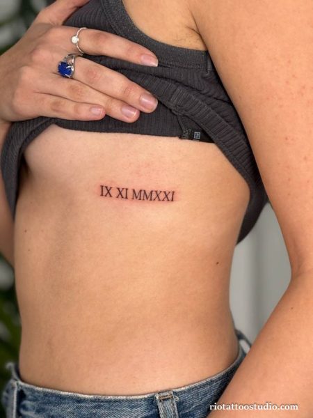 Roman numeral date IX XI MMXXI rib tattoo under breast, minimalist date rib tattoo ideas