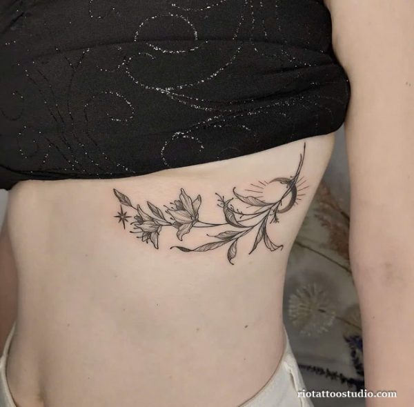 Minimalist fine line floral branch with moon and stars rib tattoo under breast, delicate rib tattoo ideas