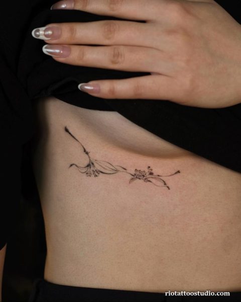 Minimalist delicate floral branch rib tattoo under breast, fine line flower tattoo ideas