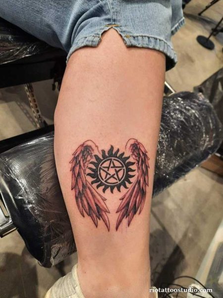 Winged anti-demon pentagram supernatural tattoo with angel wings on thigh, supernatural tattoo ideas