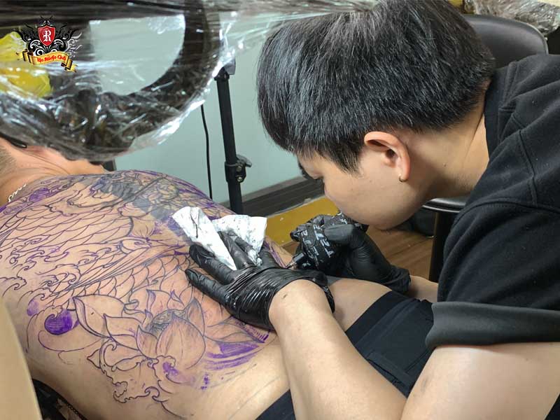 Professional artist focusing on a detailed bear tattoo at Rio Studio.