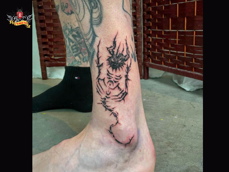 Minimal demon tattoo on the ankle of a client wearing dynamic streetwear at Rio Tattoo Studio.